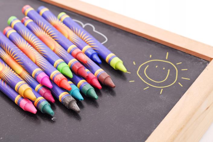 Colorful crayons on chalkboard.